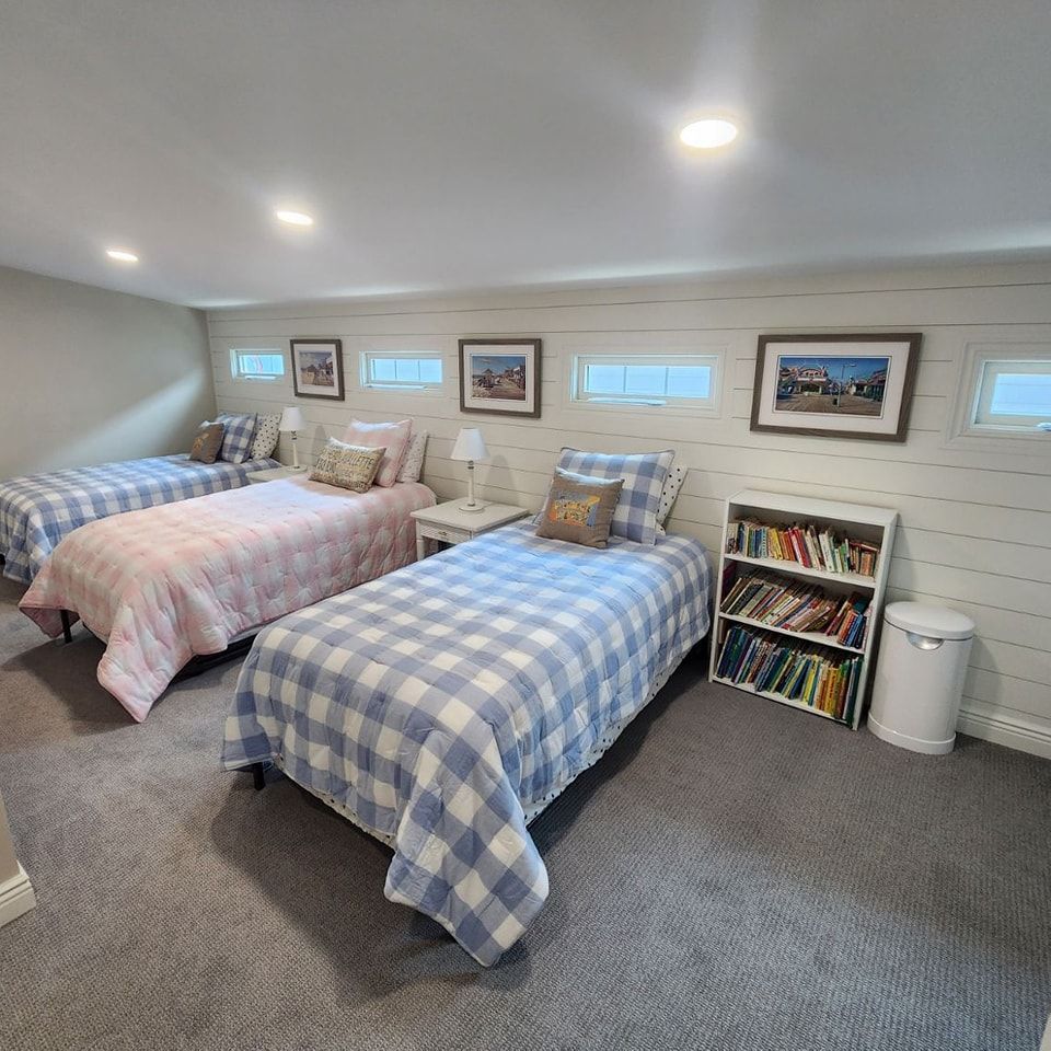 A bedroom with three beds and a bookshelf