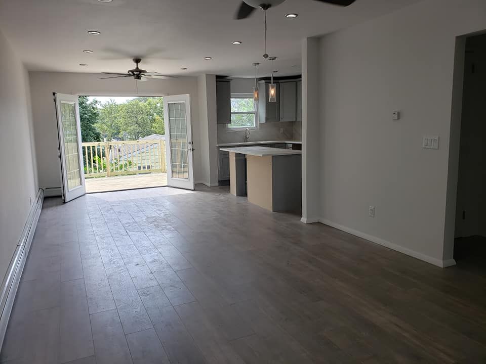 An empty living room with hardwood floors and a ceiling fan.