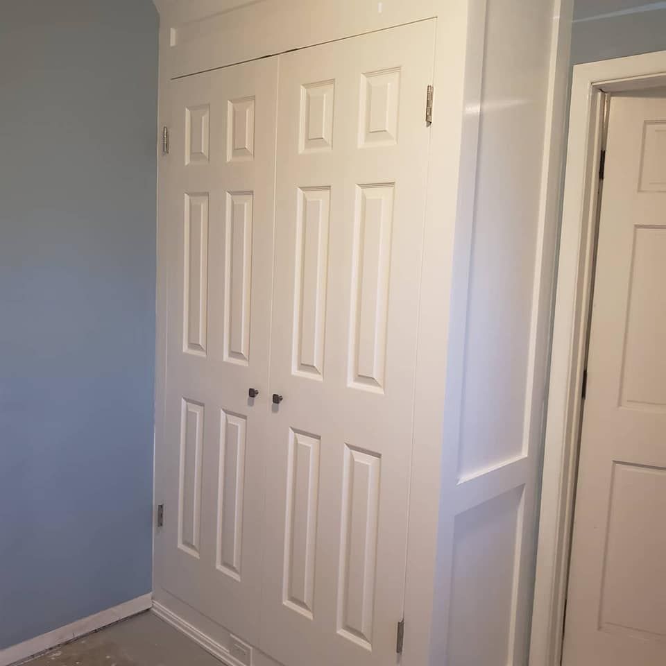 A closet with a blue wall and white doors