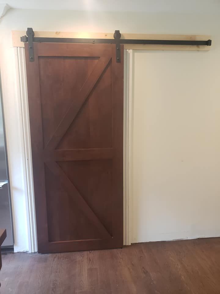 A sliding barn door is hanging on a white wall in a room.