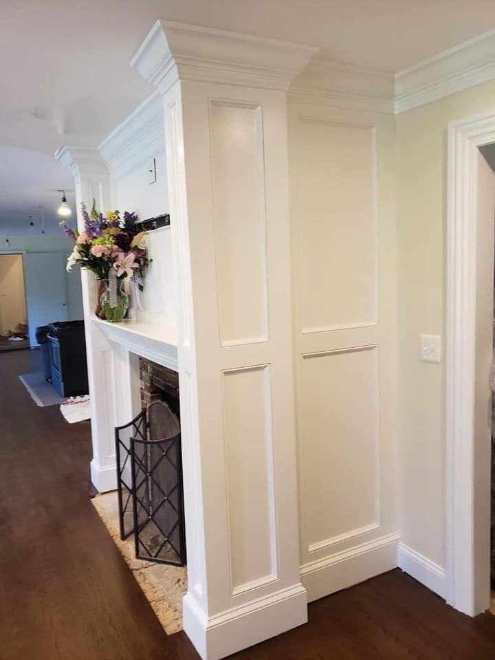 A living room with a fireplace and a vase of flowers on the mantle.