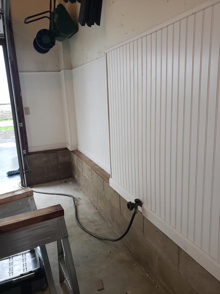 A white wall with a cord plugged into it in a garage.