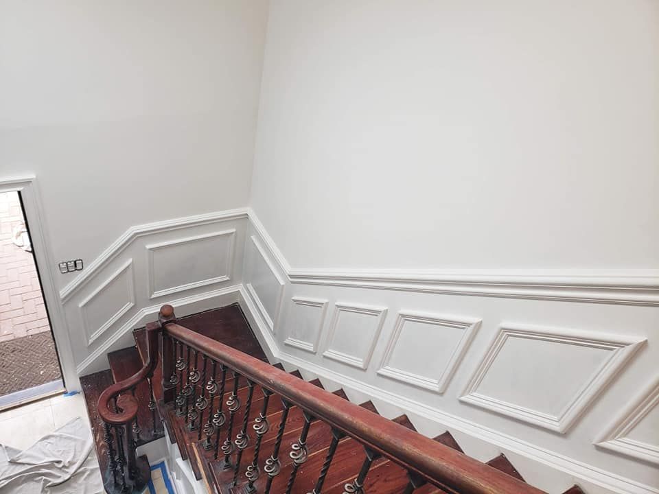 A staircase with a wooden railing and white walls.