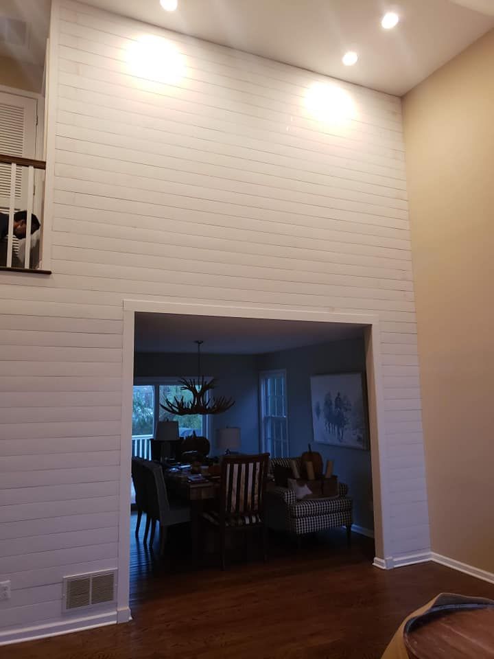 A living room with a white brick wall and a dining room in the background.