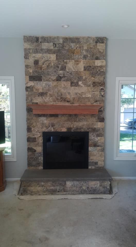 A living room with a stone fireplace and a television.