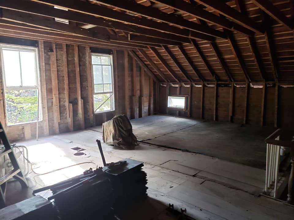 An empty attic with wooden beams and windows.