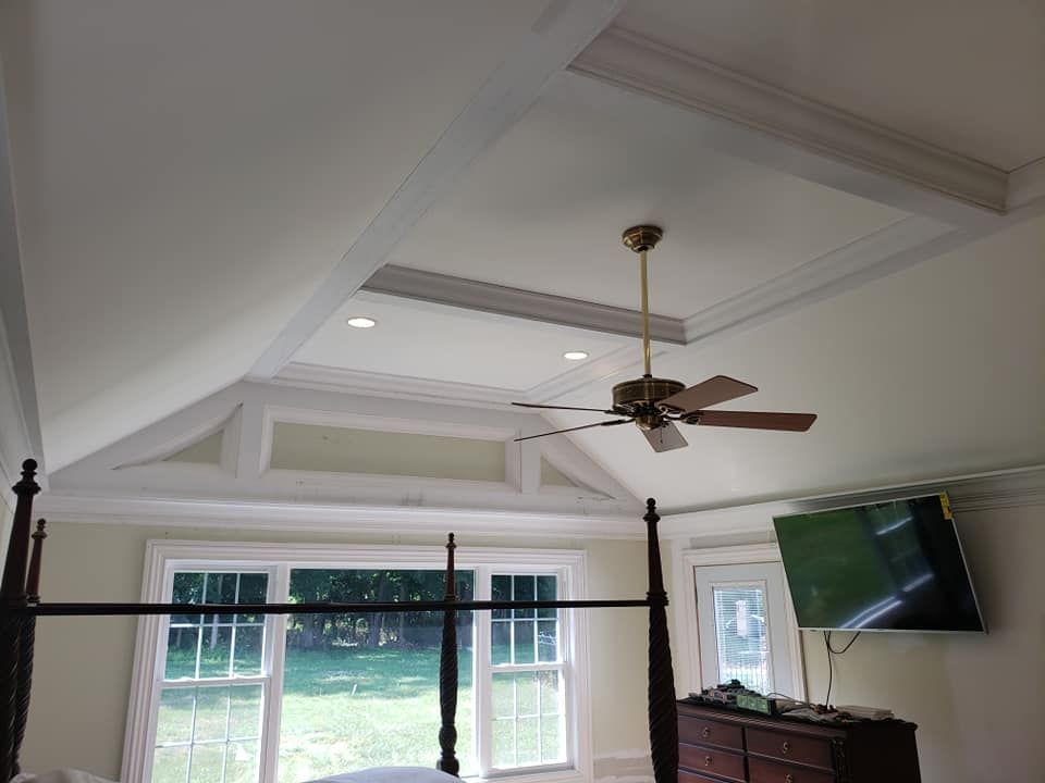 A bedroom with a canopy bed , ceiling fan and television.