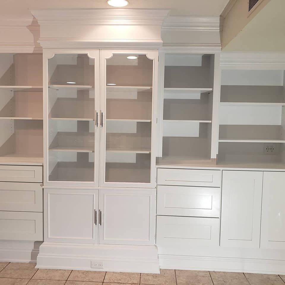 A white cabinet with glass doors and shelves in a room