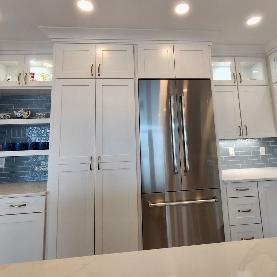 A kitchen with white cabinets and a stainless steel refrigerator