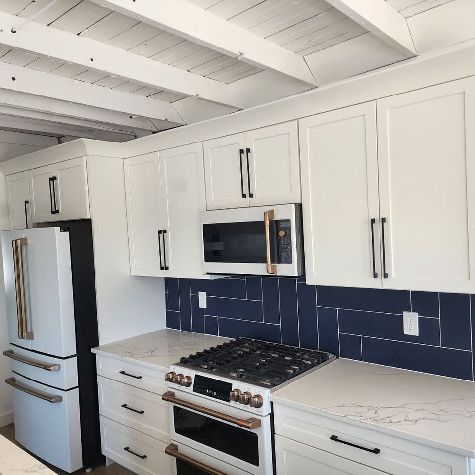 A kitchen with white cabinets a stove a refrigerator and a microwave