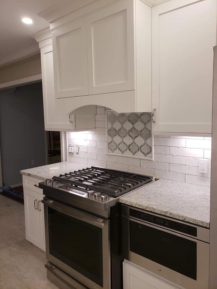A kitchen with white cabinets , a stove , and a dishwasher.