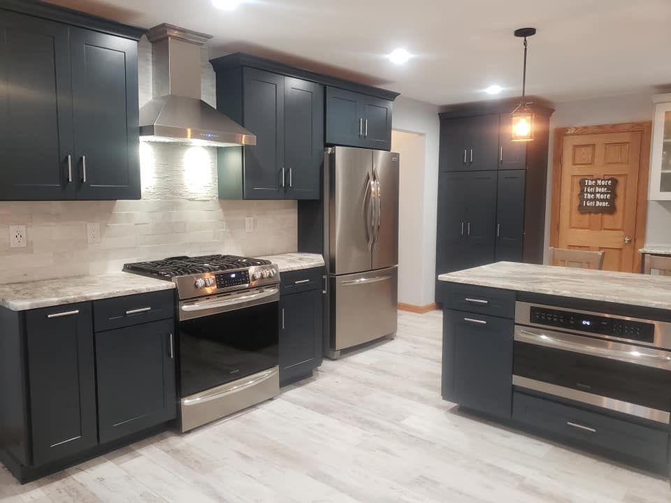 A kitchen with black cabinets and stainless steel appliances