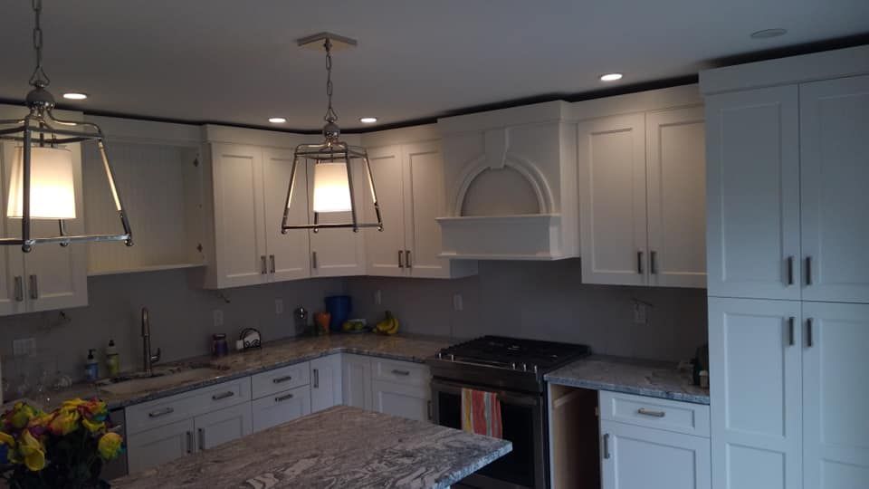 A kitchen with white cabinets , granite counter tops , and a stove.