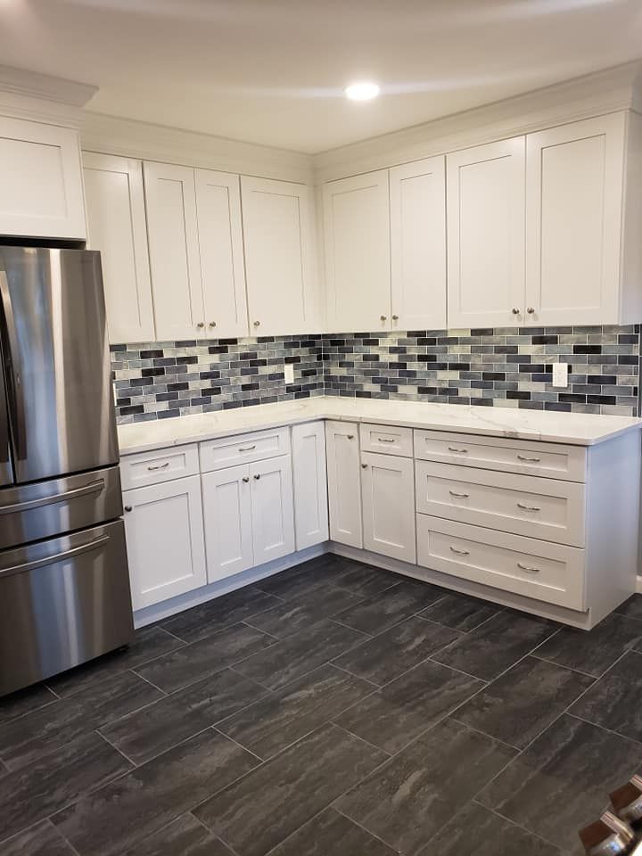 A kitchen with white cabinets and a stainless steel refrigerator.
