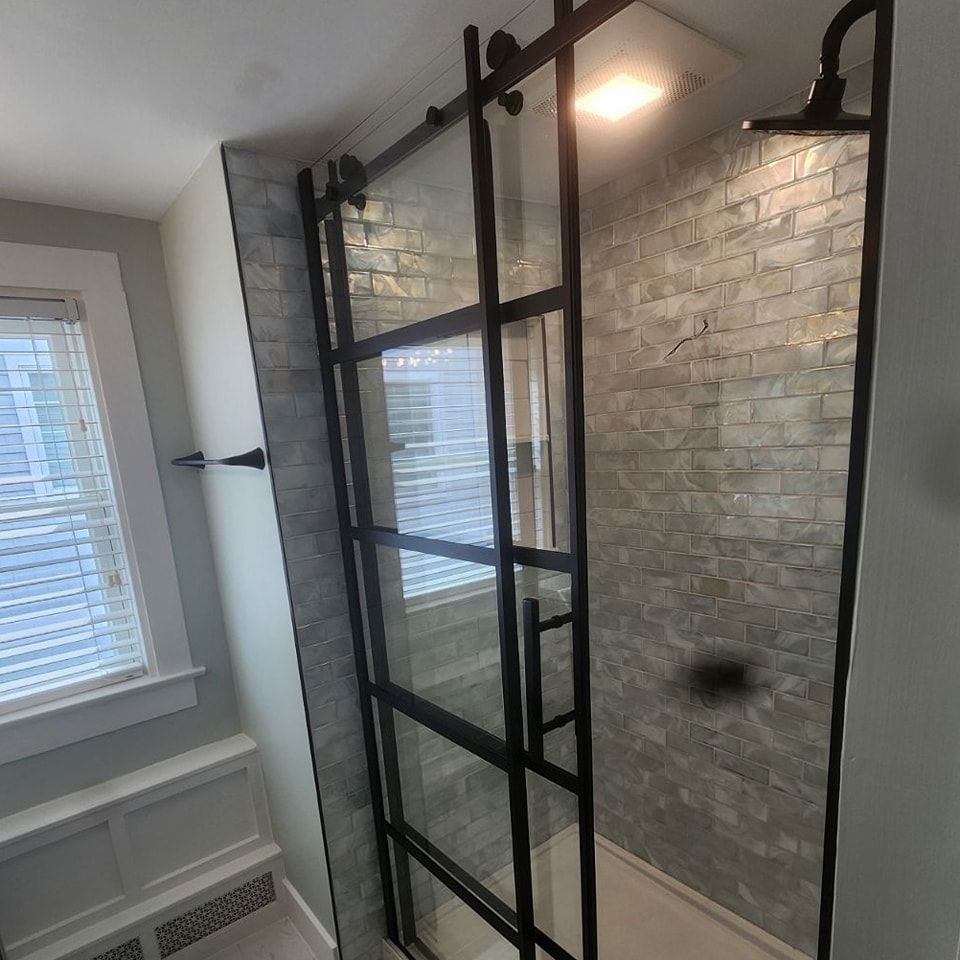 A bathroom with a sliding glass shower door and a window.