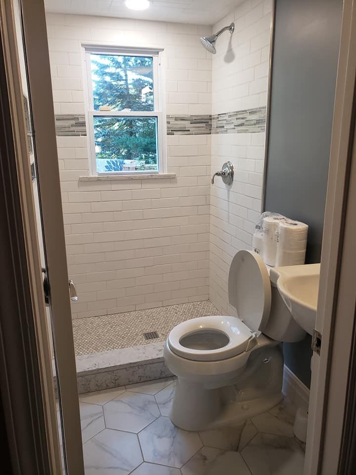 A bathroom with a toilet , sink , and shower.