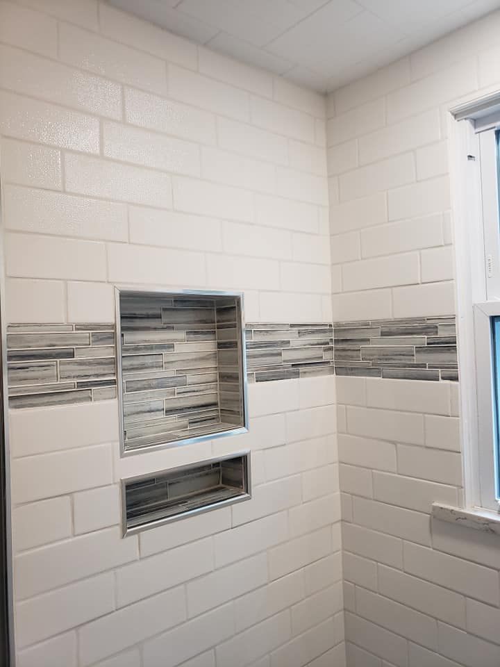 A bathroom with white tiles and a window.