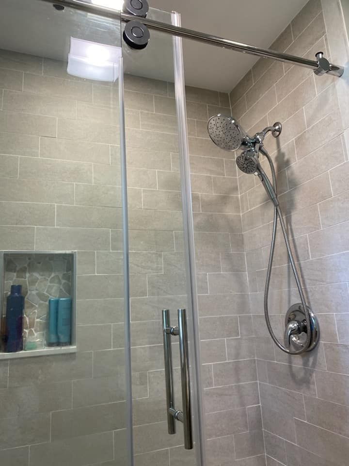 A shower with a sliding glass door and a shower head.