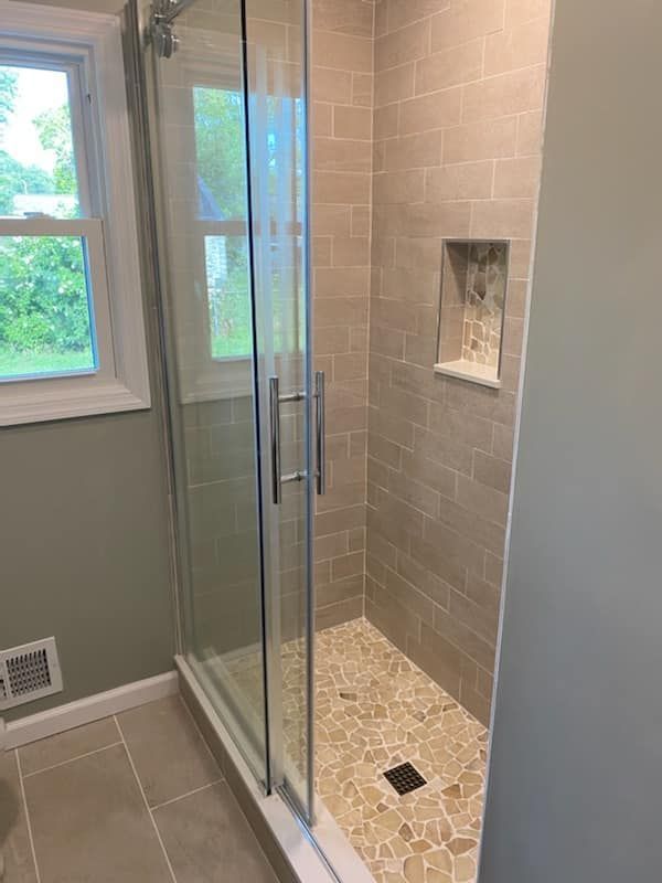A bathroom with a walk in shower and a window.
