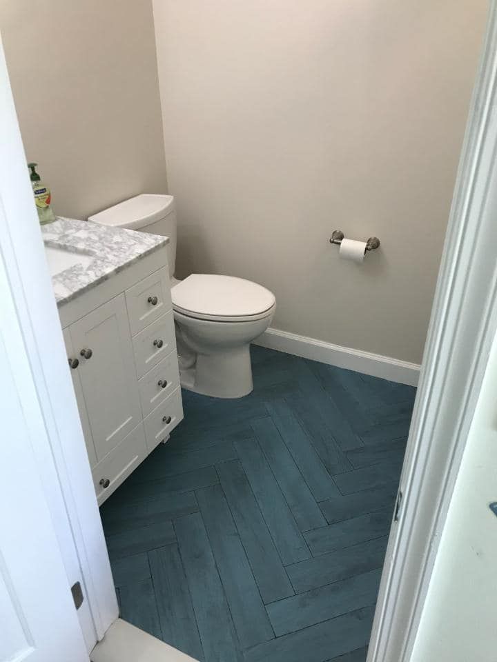 A bathroom with a toilet , sink , and blue floor.