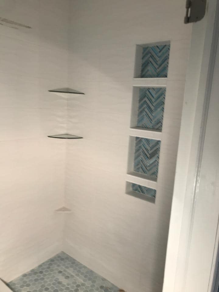 A bathroom with a walk in shower and shelves.