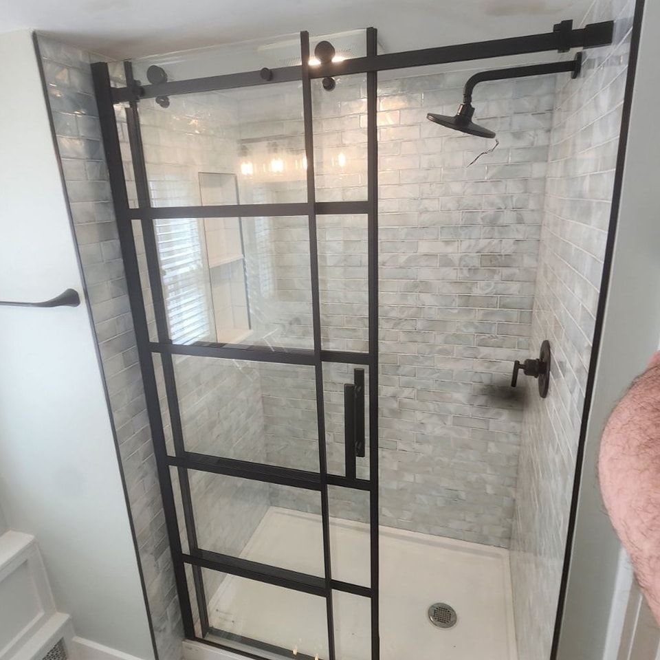 A bathroom with a sliding glass shower door and a shower head.