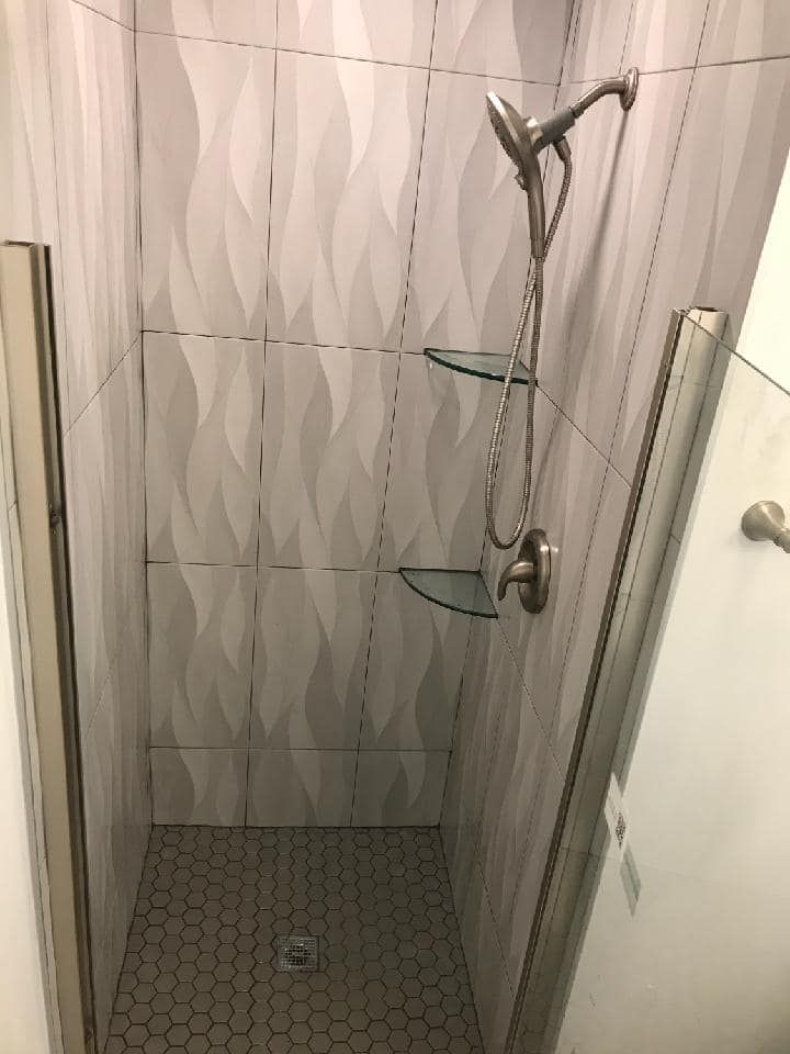 There is a shower with a glass door and a shower head.