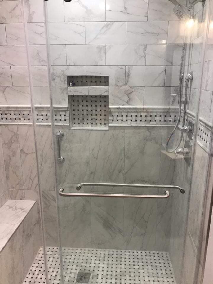 A bathroom with a walk in shower with a glass door.