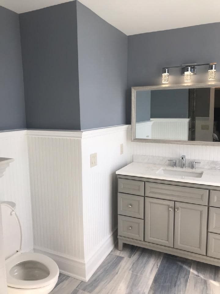 A bathroom with a toilet , sink and mirror.