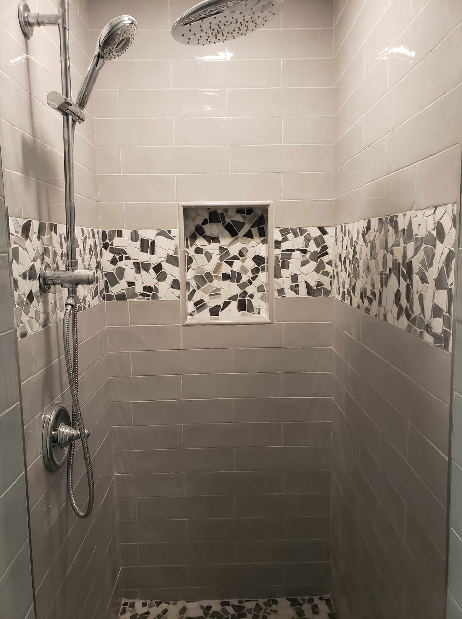 A shower with a shower head and a tiled wall.