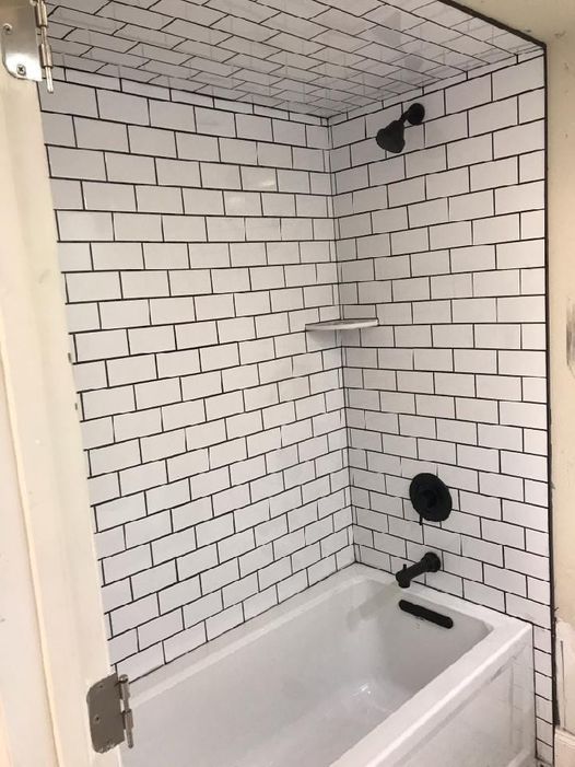 A bathroom with white subway tiles and a bathtub.