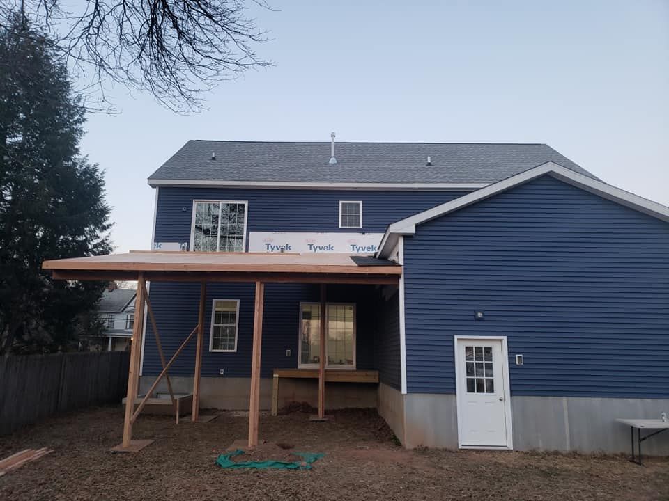 A blue house with a white door and a wooden deck