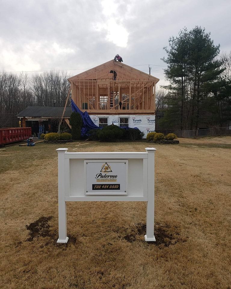 A white sign in front of a house under construction