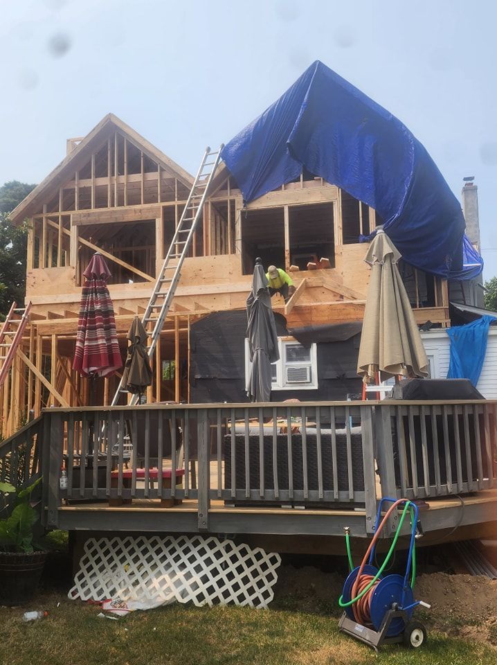 A house under construction with a blue tarp on top of it