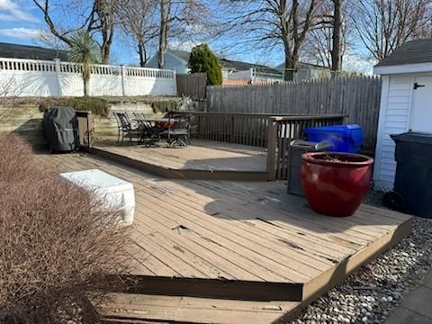 A wooden deck with a table and chairs on it in a backyard.