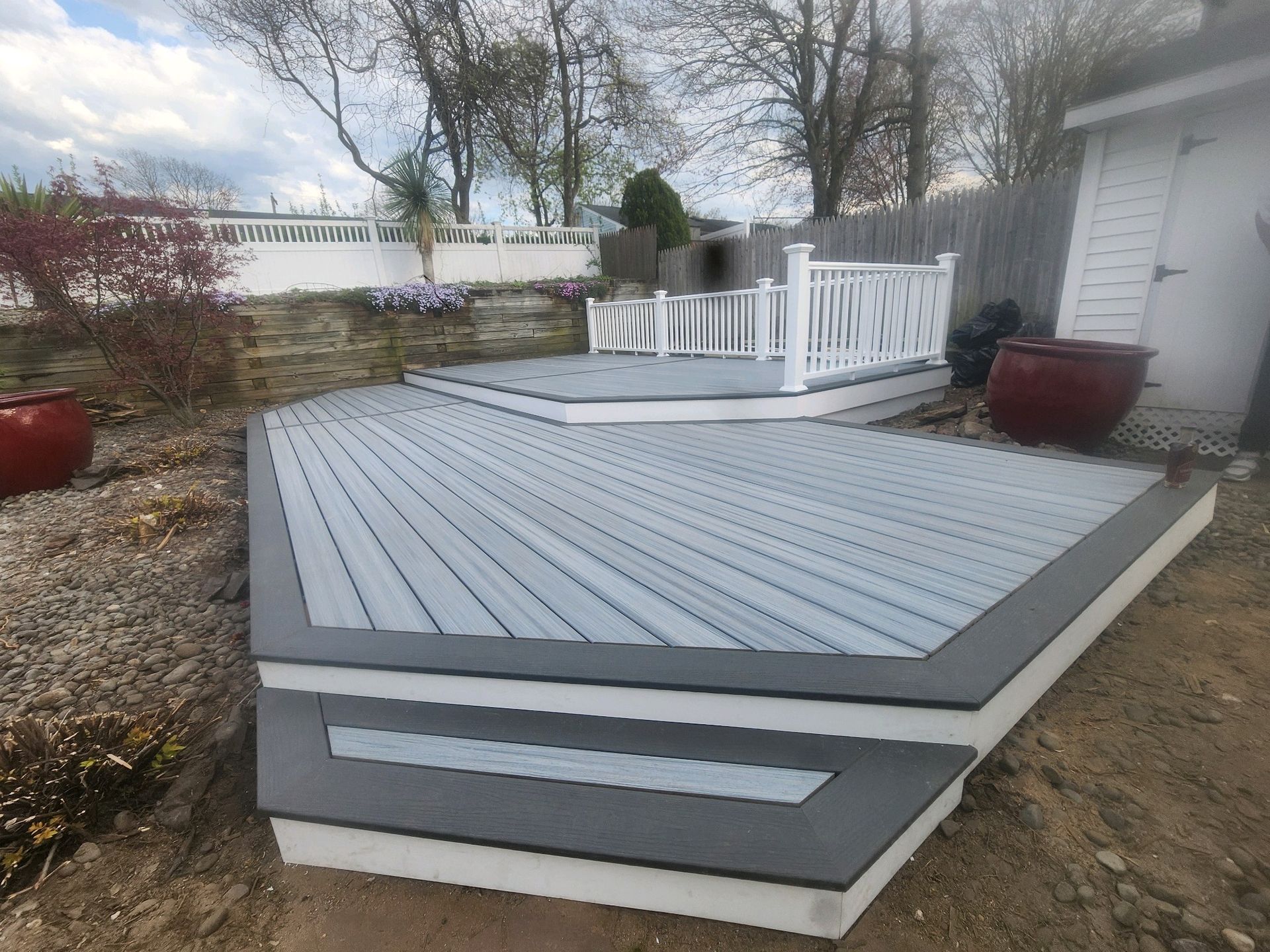 A gray and white deck with a white railing in the backyard.
