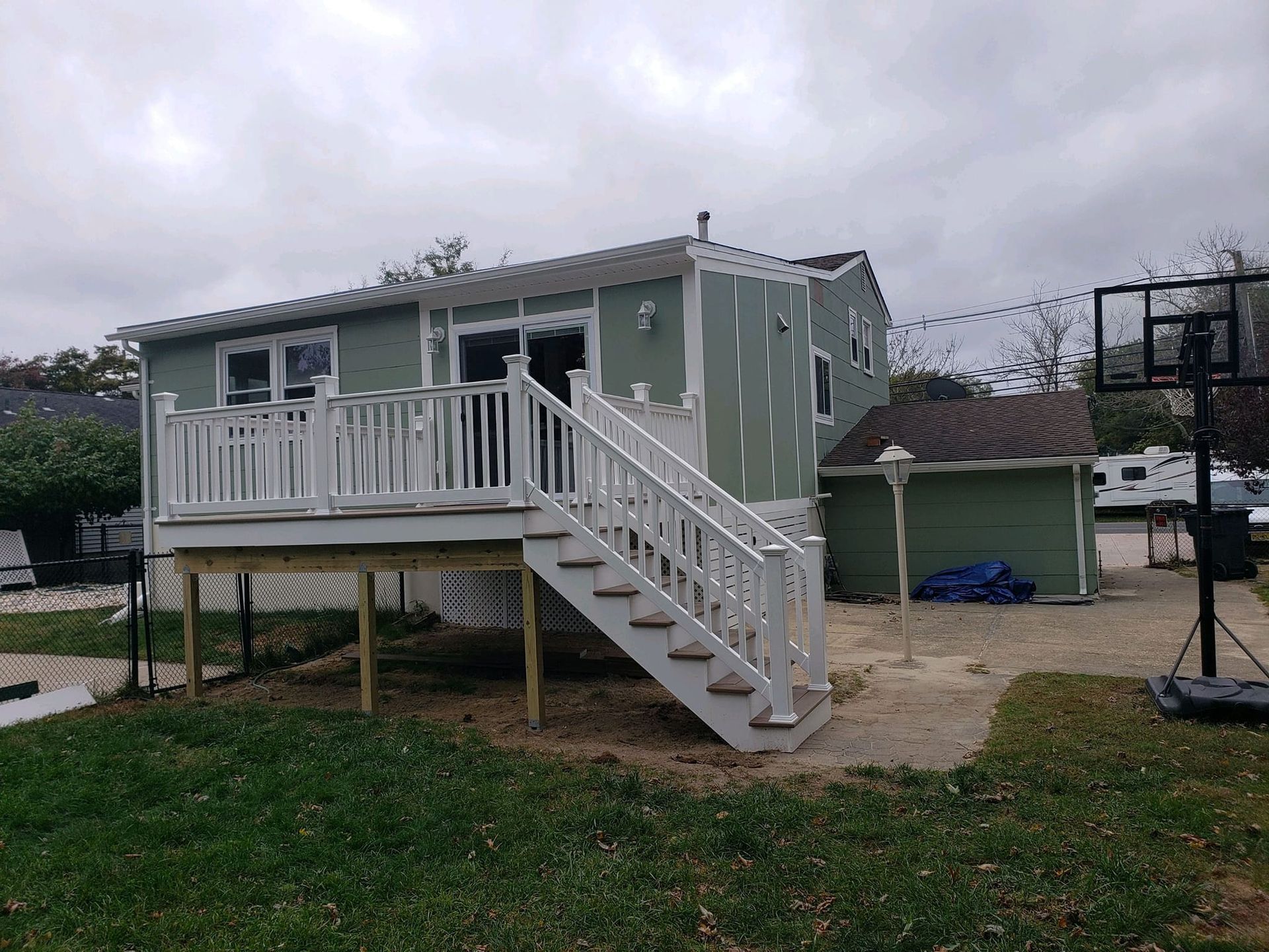 A green house with a white deck and stairs.