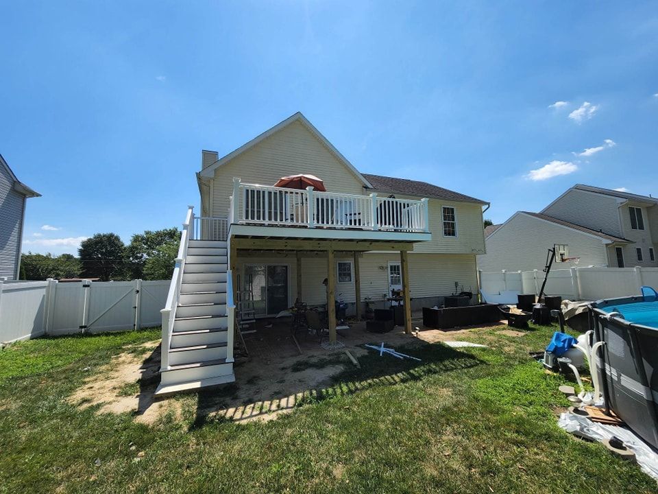 A house with a large deck and stairs in the backyard.