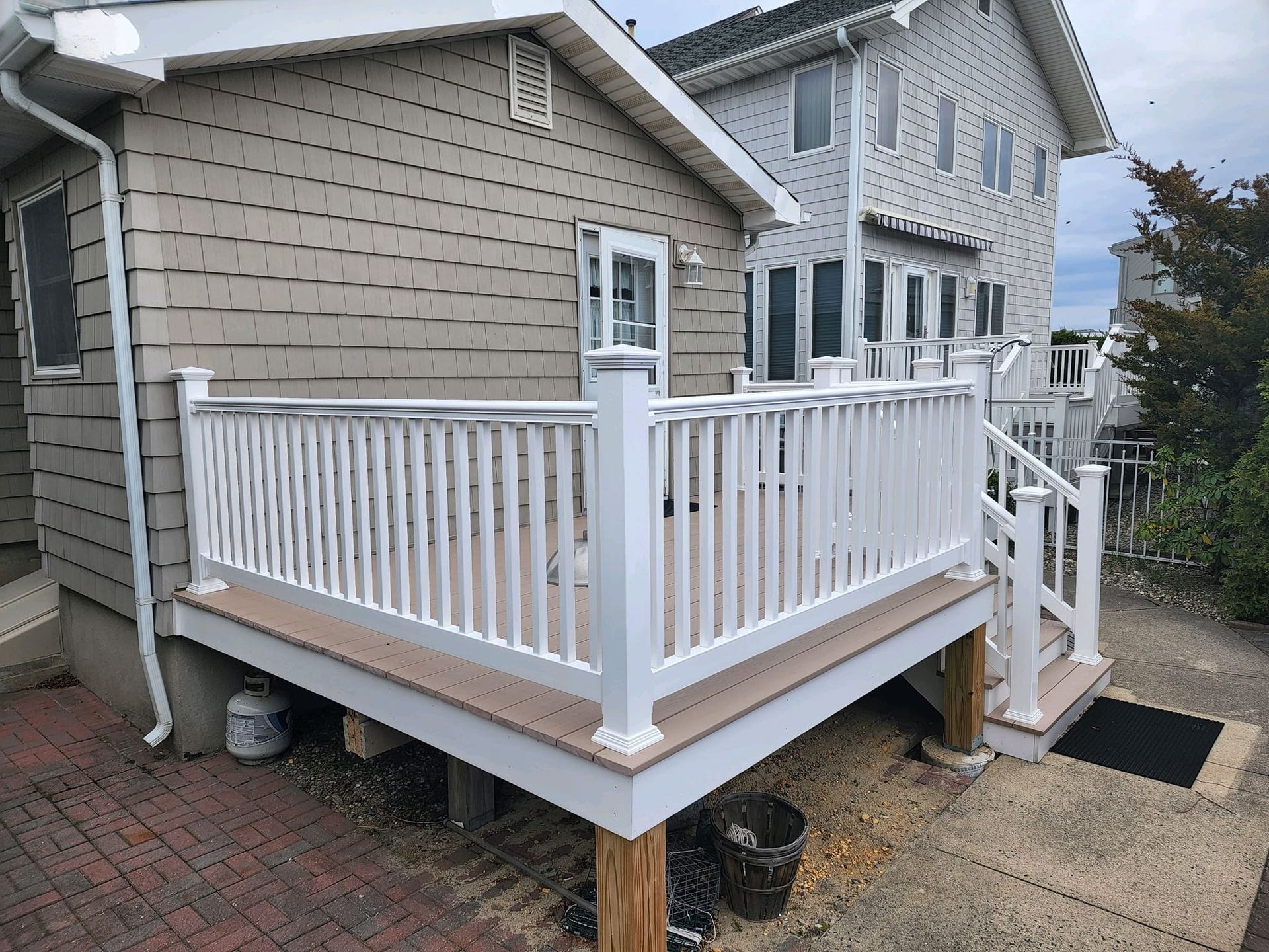 A white deck with stairs is in front of a house.