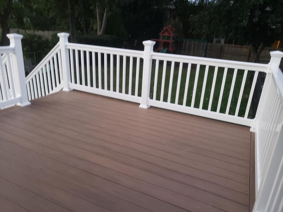 A deck with a white railing and a playground in the background