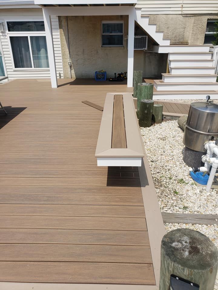 A wooden deck with a bench and stairs in the background.