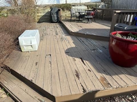 A wooden deck with a red pot and a white cooler on it.