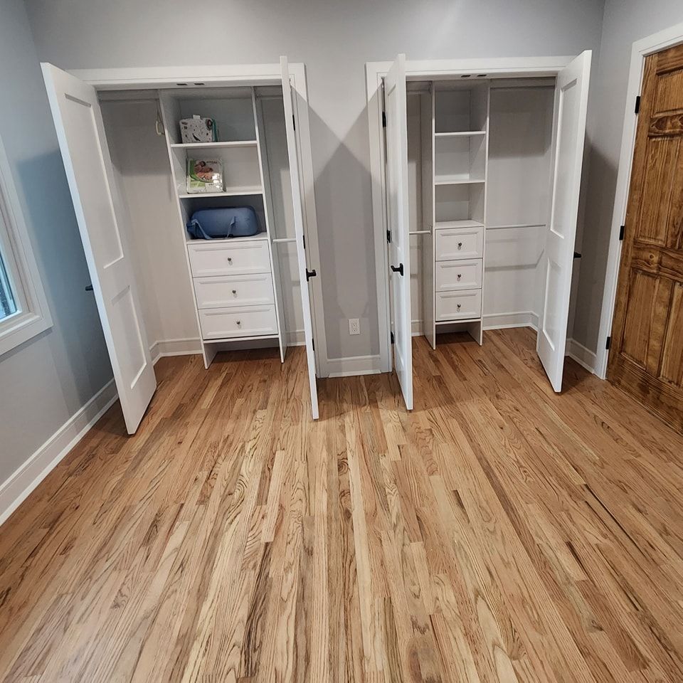 A room with hardwood floors and two closets with the doors open