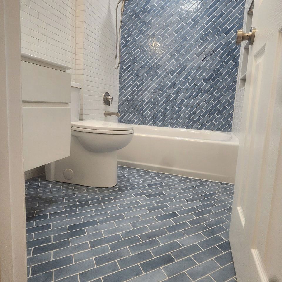 A bathroom with blue tiles and a toilet