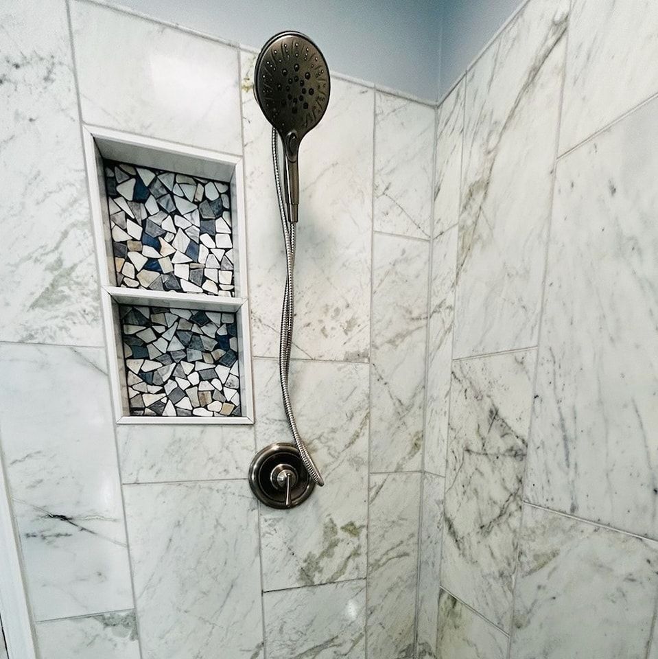 A shower head in a bathroom with marble tiles