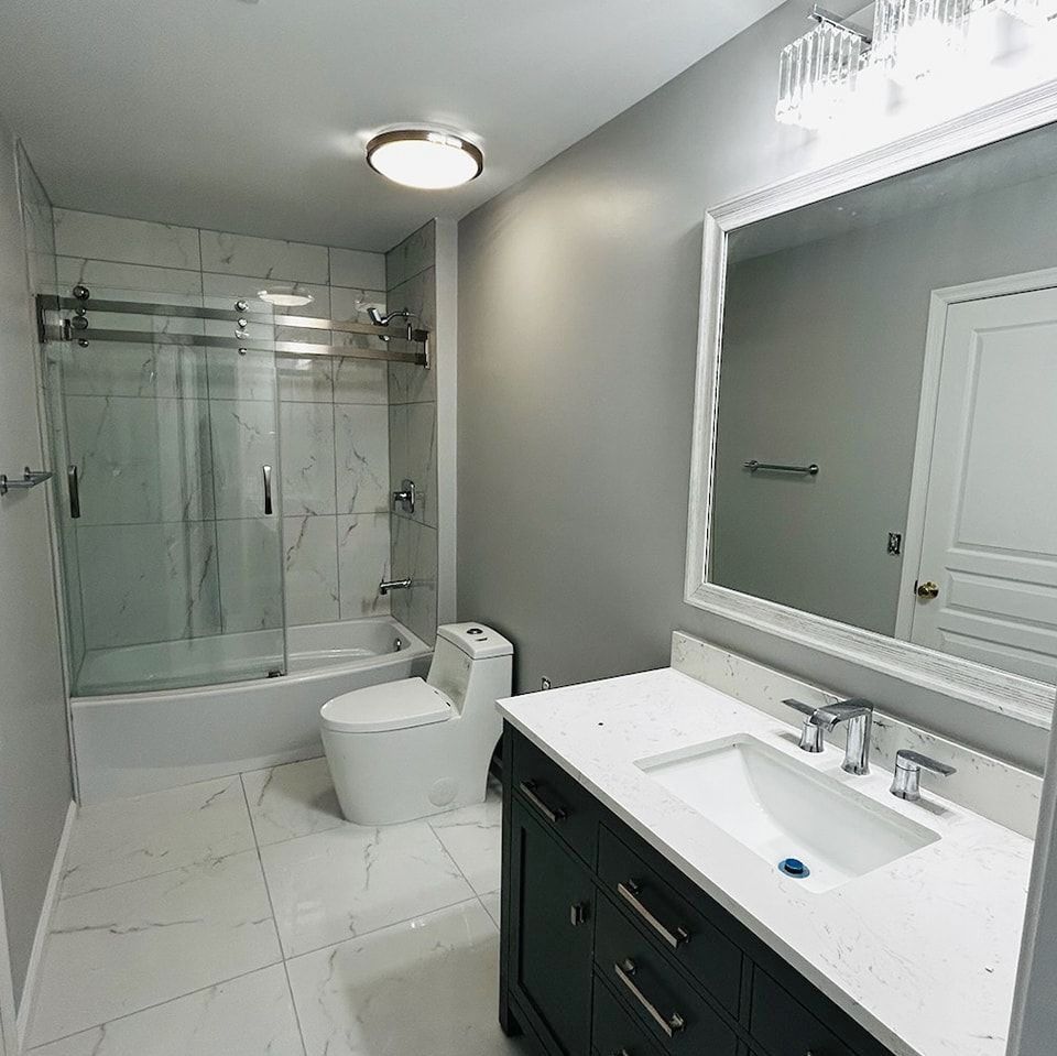 A bathroom with a toilet, sink, shower, and mirror