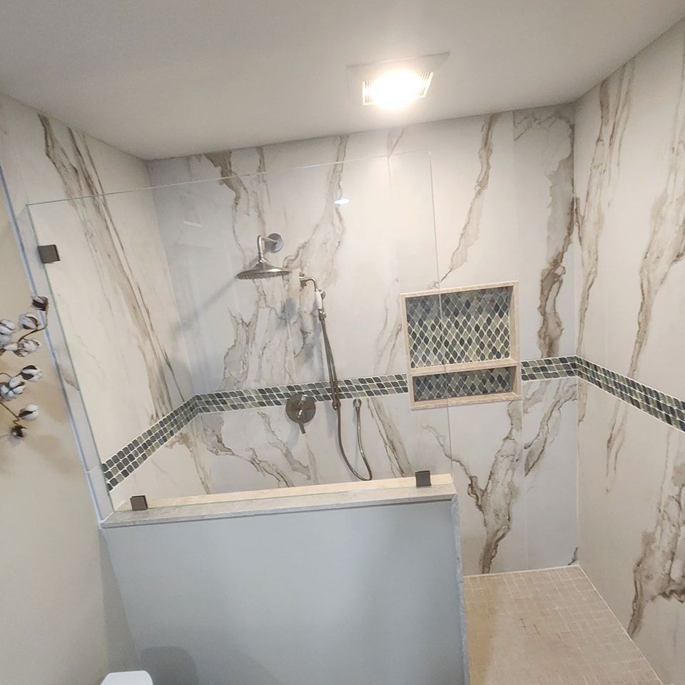 A bathroom with marble walls and a walk in shower