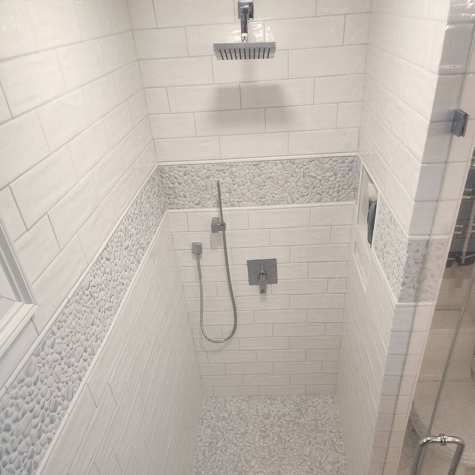 A bathroom with white tiles and a shower head