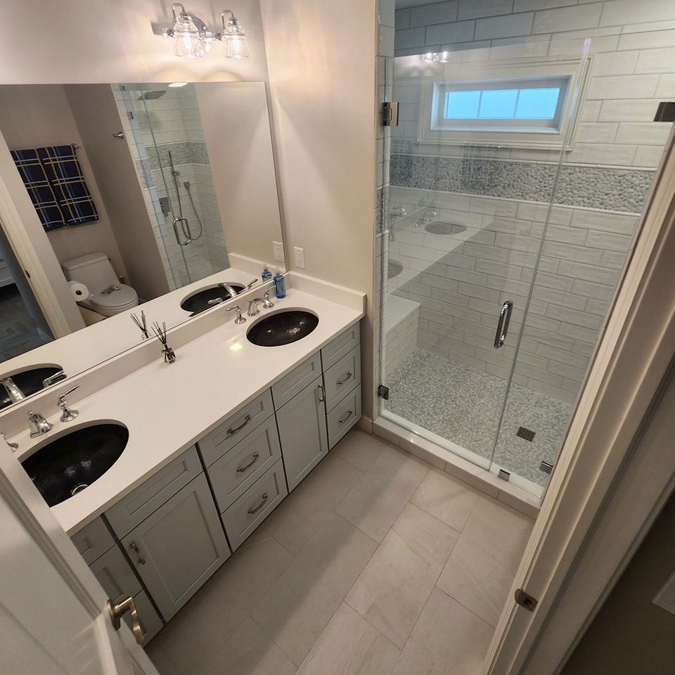 A bathroom with two sinks and a walk-in shower