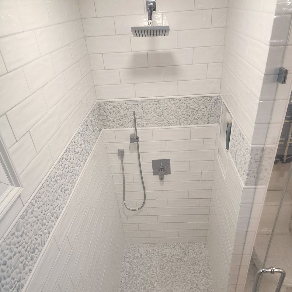 A shower stall with white tiles and a shower head